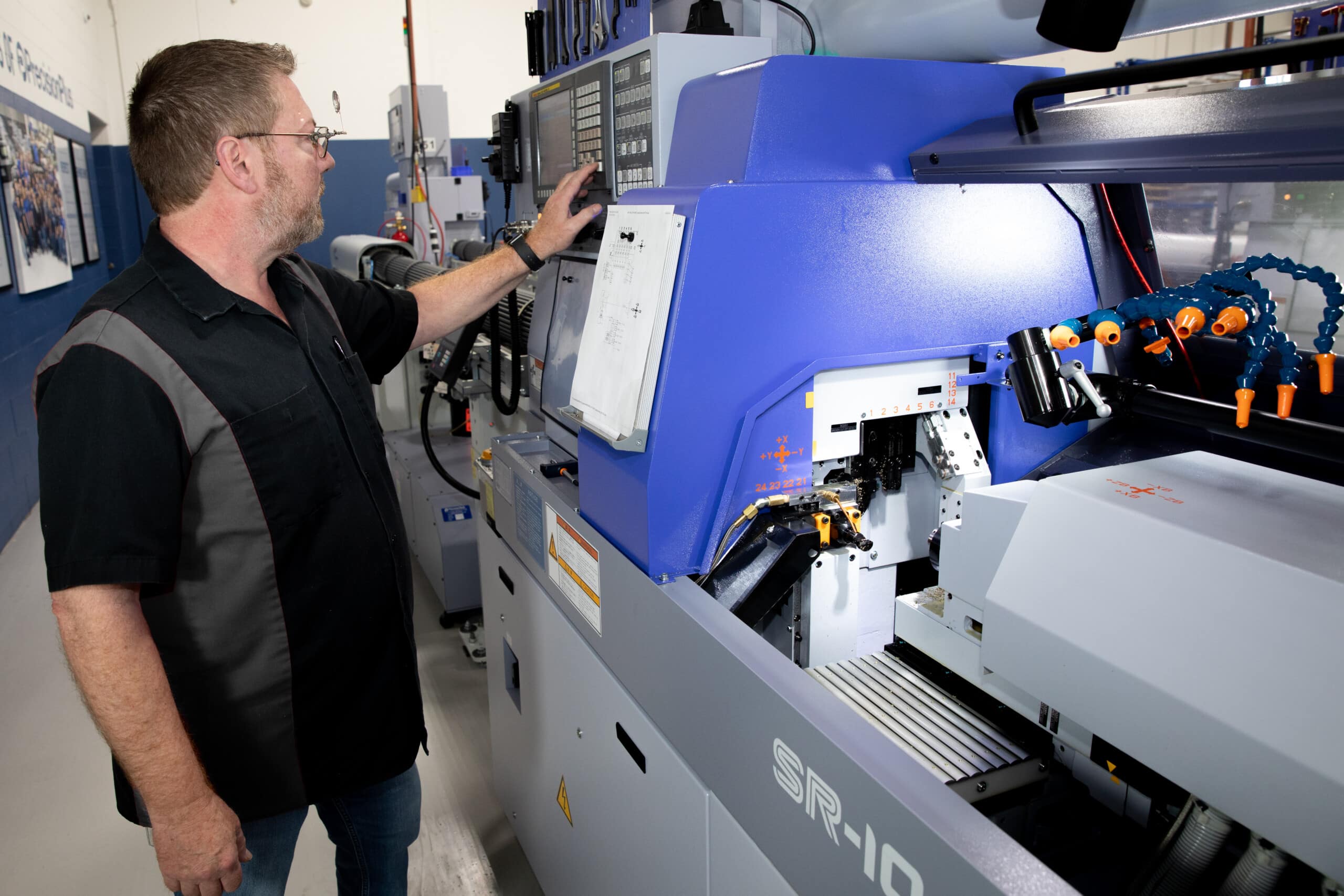 CNC Machinist standing next to Star SR-10 machine, pressing buttons.